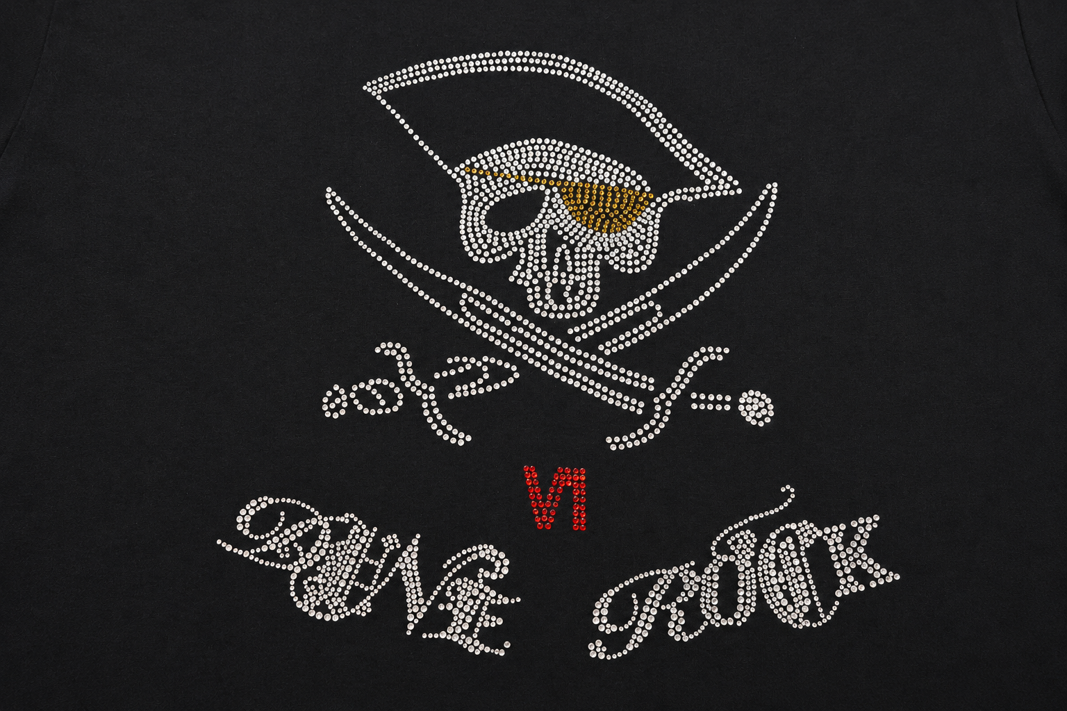 Rhinestone skull and crossed swords motif with gold, red, and clear stones on black fabric