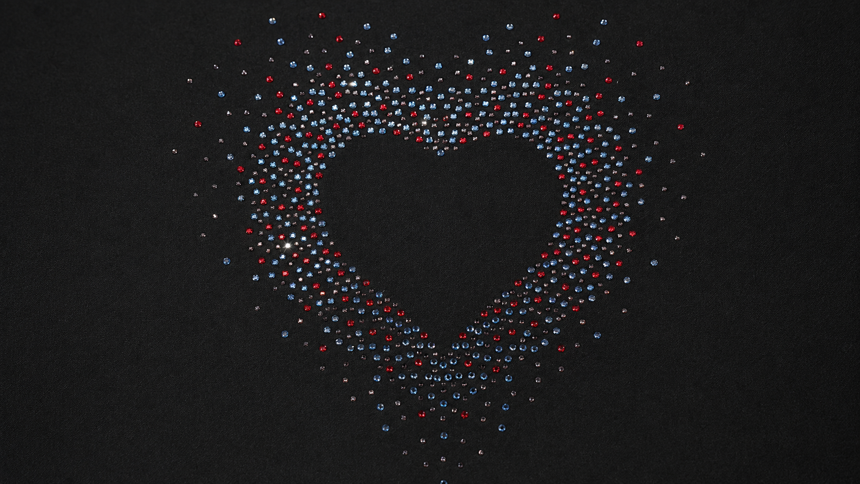 Red, blue, and clear rhinestone heart motif arranged on black fabric